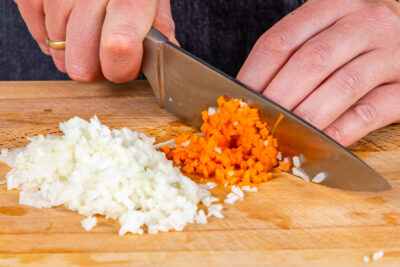 Zwiebeln, Knoblauch und Möhren klein schneiden für Bulgur-Bratlinge