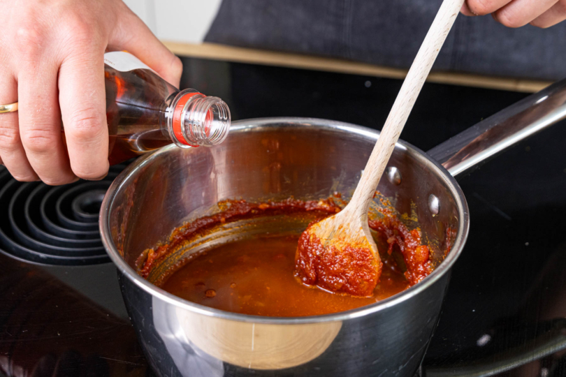 Apfelessig und gehackte Tomaten in den Topf geben und aufkochen