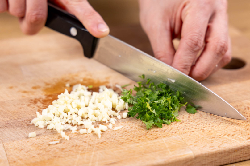 Knoblauch und Petersilie fein hacken
