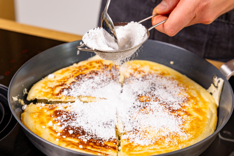 Puderzucker über Holunderblüten-Kaiserschmarrn sieben