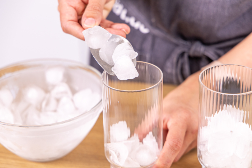 Eiswürfel ins Glas geben