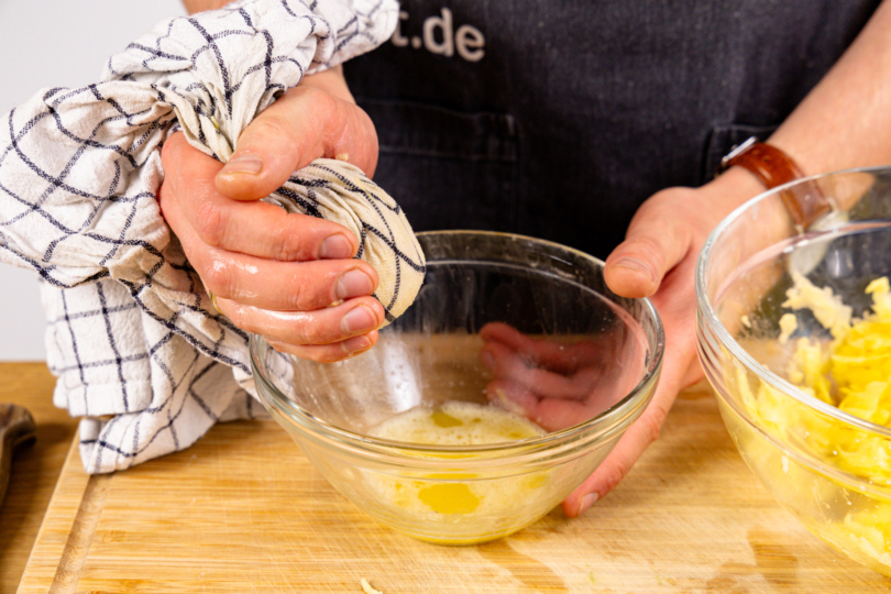 geraspelte Kartoffeln mit einem Geschirrtuch entwässern