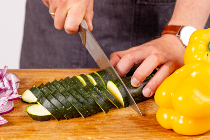 Zucchini längs halbieren und in Scheiben schneiden
