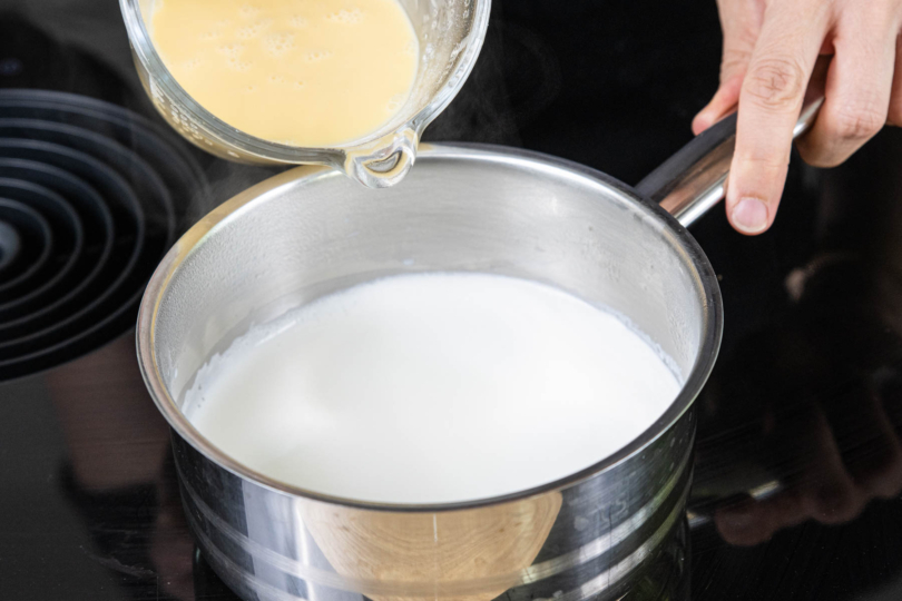 Pudding in die köchelnde Milch geben