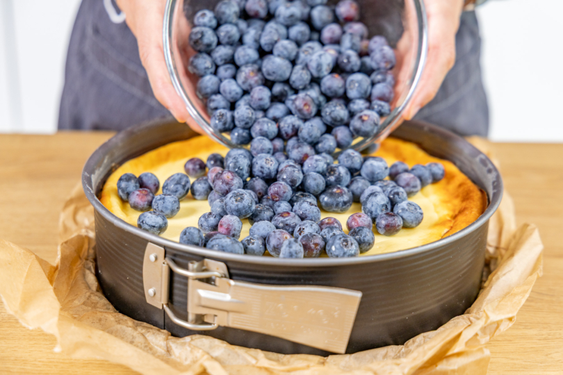 Blaubeeren auf dem Käsekuchen verteilen