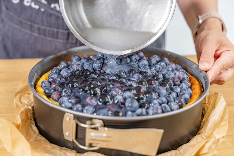 Tortenguss auf den Blaubeeren verteilen