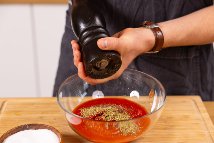 Passierte Tomatensauce würzen.