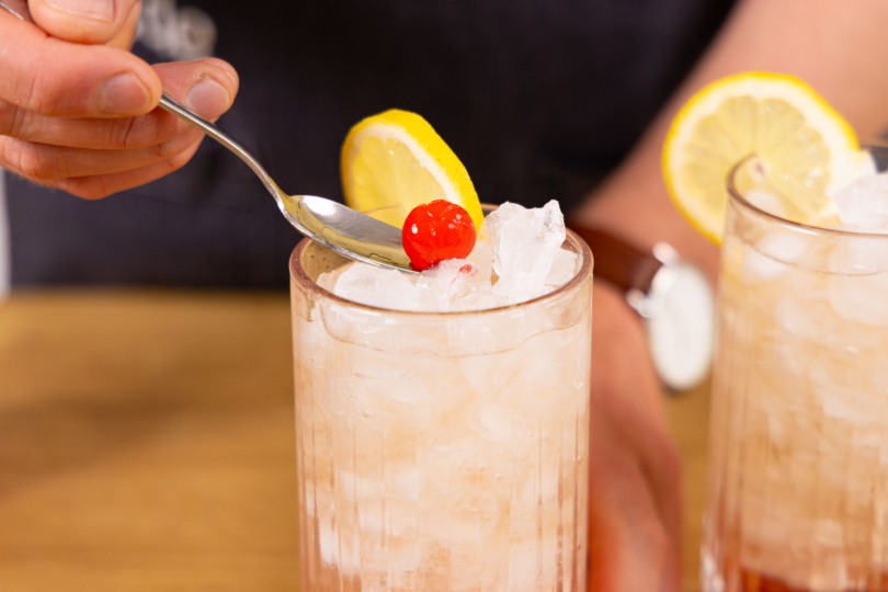 Mit Cocktailkirsche garnieren.
