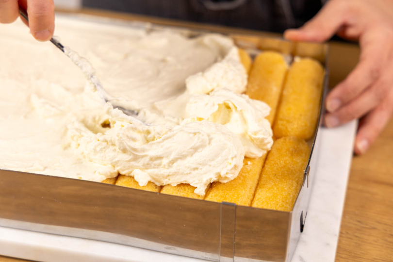 Creme auf Löffelbiskuits streichen