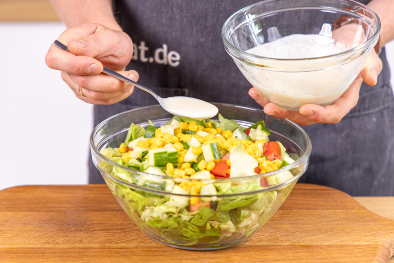 Blattsalat mit Joghurtdressing vermengen