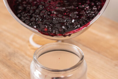 Blaubeermarmelade in ein Glas geben