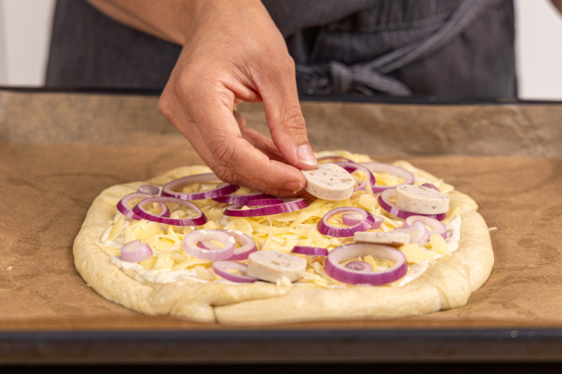 Weißwurst auf Brezel Pizza legen