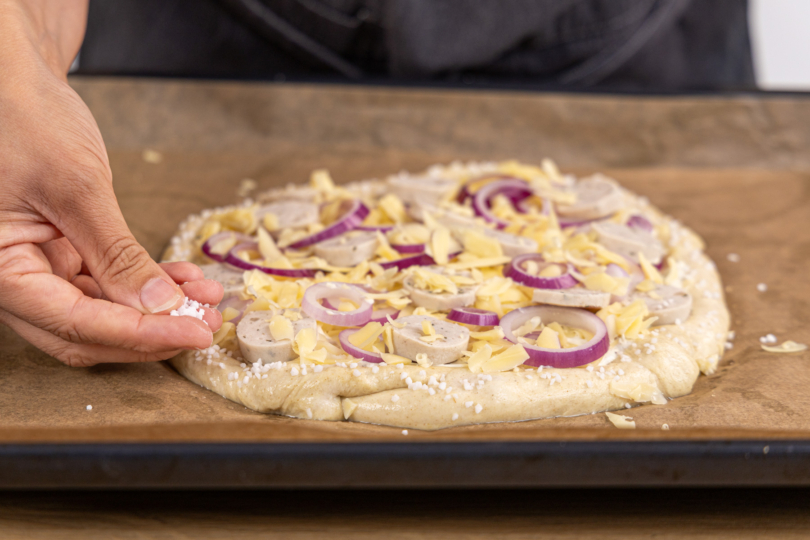 Brezel Pizza Rand mit Salz bestreuen