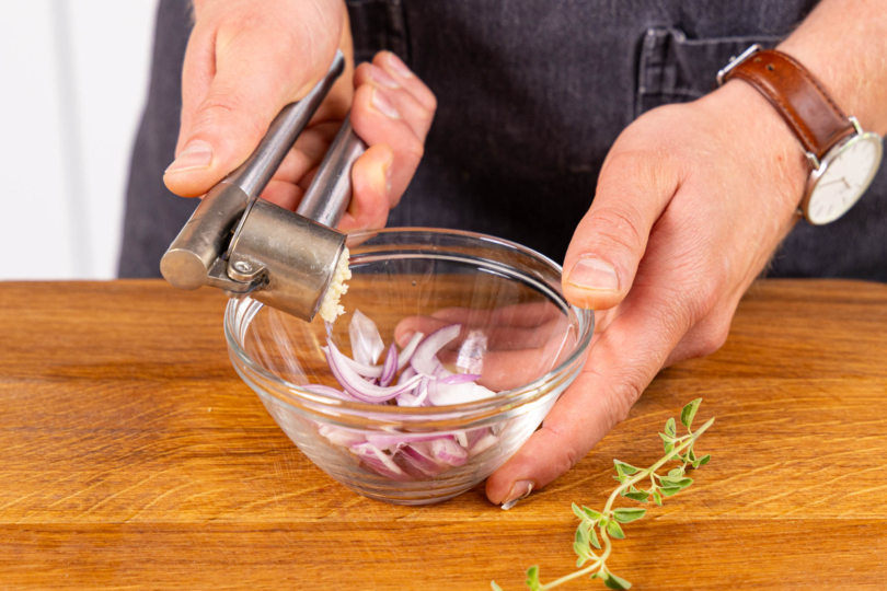 Knoblauch zu den Zwiebelstreifen pressen
