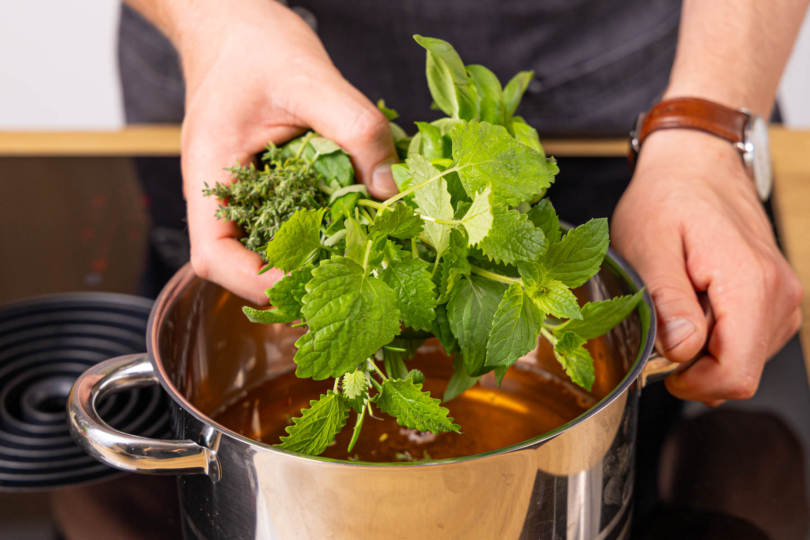 Kräuter zum Apfelsaft geben und aufkochen