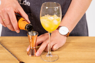 Maracujasaft und Prosecco ins Glas geben