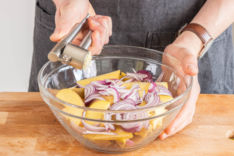 Knoblauch in die Schüssel pressen