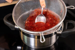 Stachelbeermarmelade durch Sieb drücken