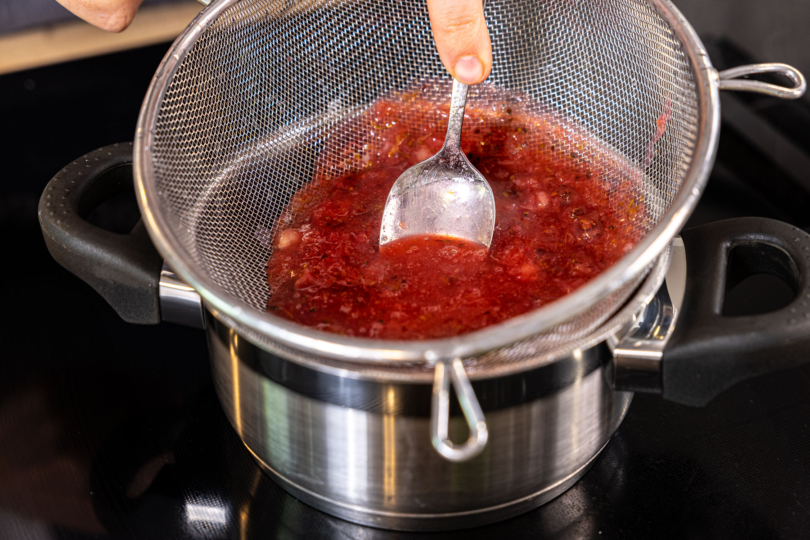 Stachelbeermarmelade durch Sieb drücken