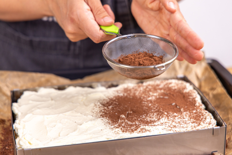 Tiramisu-Brownies mit Backkakao bestreuen