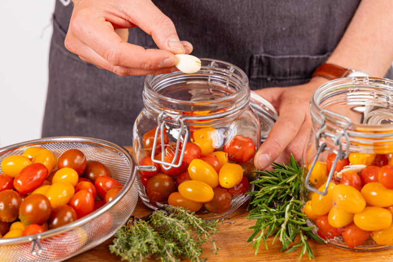 Kräuter und Knoblauch zu den Tomaten geben