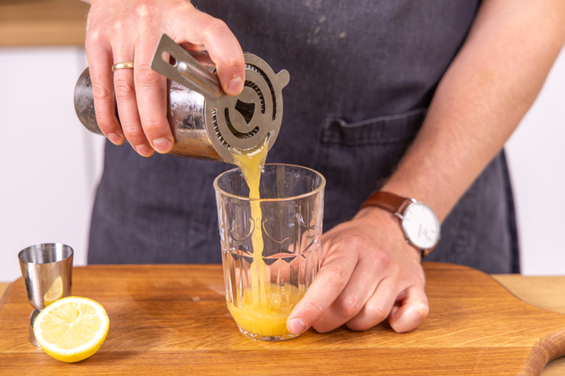 Saft durch ein Sieb in Glas füllen