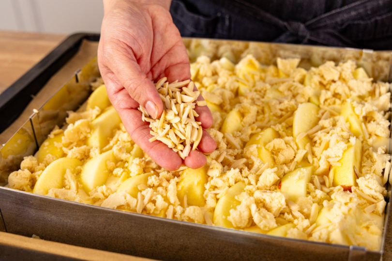 Mandelsplitter auf dem Apfelkuchen verteilen