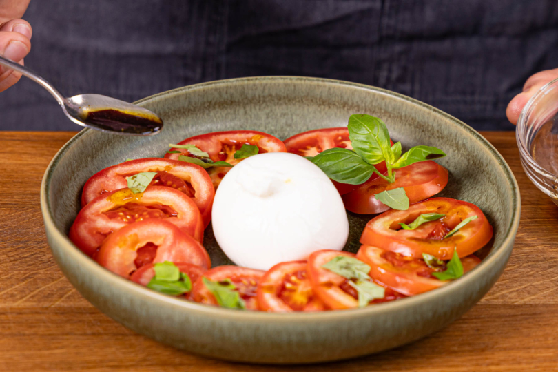 Dressing über Tomaten träufeln.