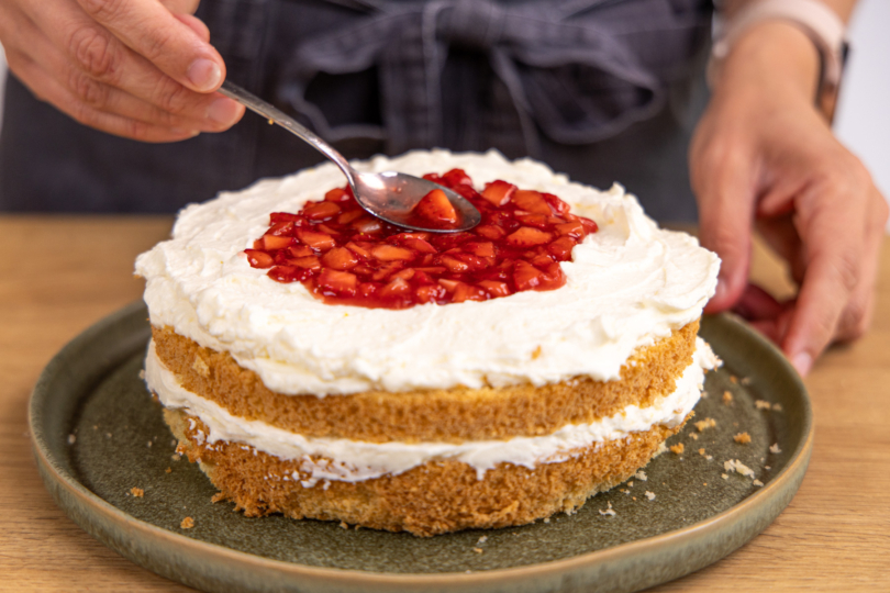 Biskuit mit Erdbeer-Masse und Creme bestreichen