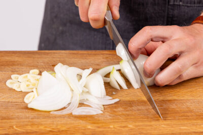 Knoblauch und Zwiebeln in Scheiben bzw. Streifen schneiden