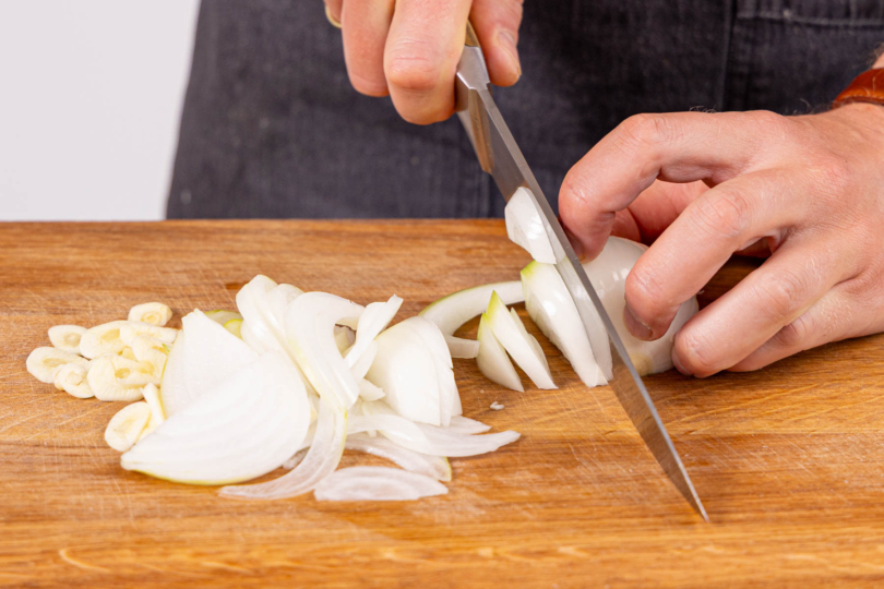 Knoblauch und Zwiebeln in Scheiben bzw. Streifen schneiden