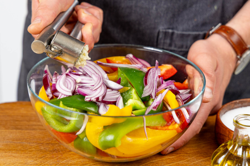 Knoblauch zum Paprikagemüse pressen