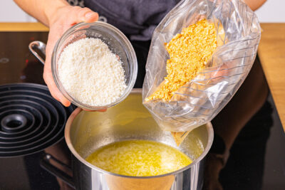 Keksbrösel und Kokosrapel in die flüssige Butter geben