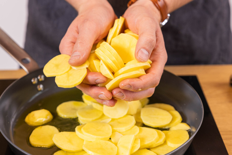 Kartoffelscheiben in die Pfanne geben