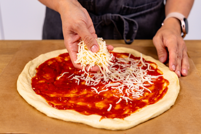 Pizzaboden mit Sauce und Käse belegen