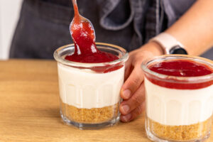 Marmeladenschickt auf den Käsekuchen im Glas geben
