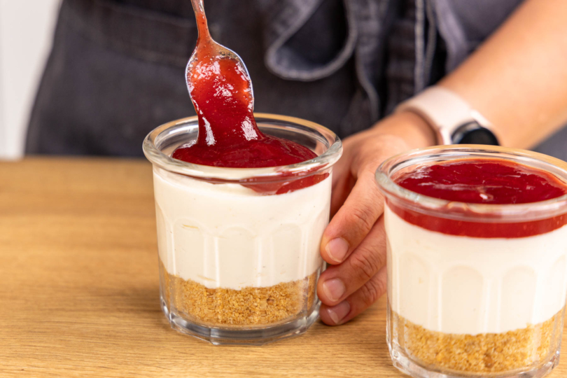 Marmeladenschickt auf den Käsekuchen im Glas geben
