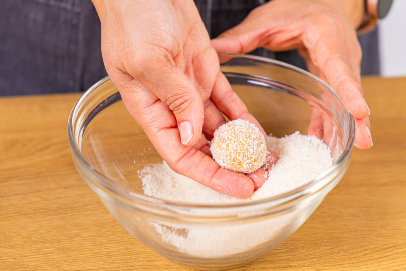 Käsekuchen-Kugeln in Kokosraspeln wälzen