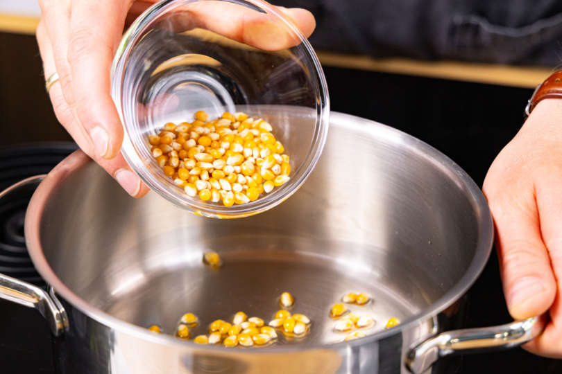 Popcorn-Mais in den Topf geben.