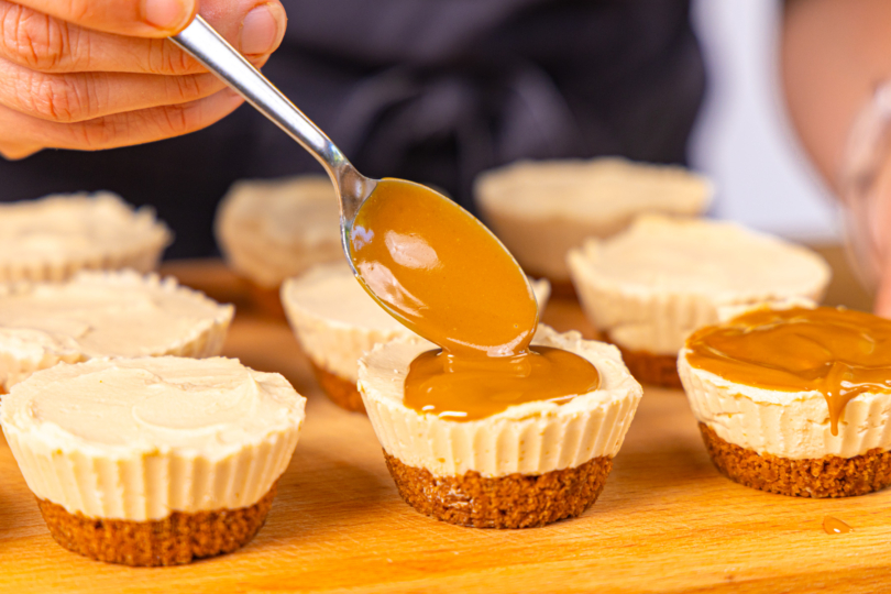 Karamellcreme als Topping auf die Lotus Biscoff Mini Cheesecakes verteilen