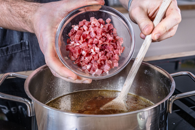 Schinkenwürfel in den Topf geben