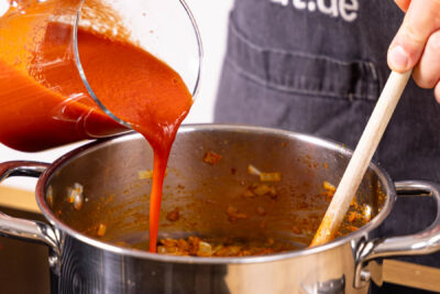 passierte Tomaten, Joghurt und Gemüsebrühe in den Topf geben.