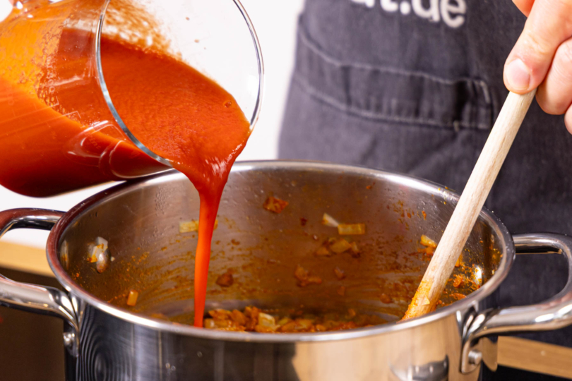passierte Tomaten, Joghurt und Gemüsebrühe in den Topf geben.