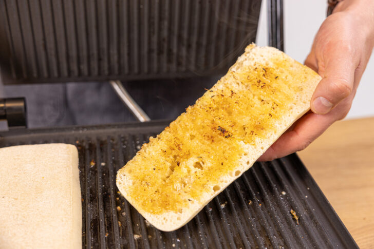 Paninibrot mit Margarine im Kontaktgrill rösten