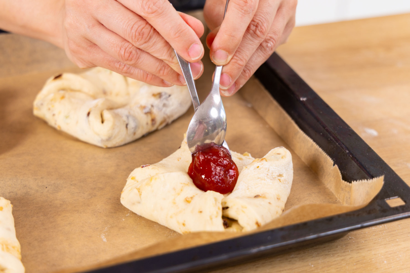 Marmelade auf Reformationsbrötchen verteilen