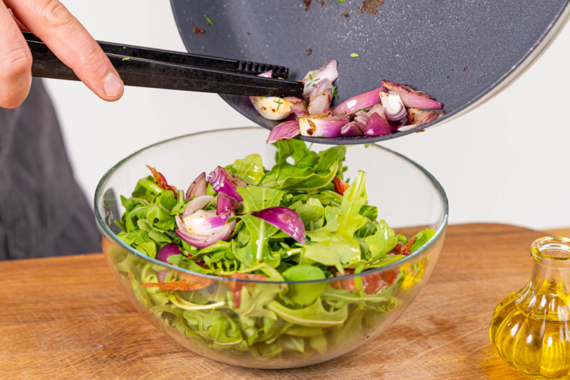Bacon und Zwiebel zum Rucola geben