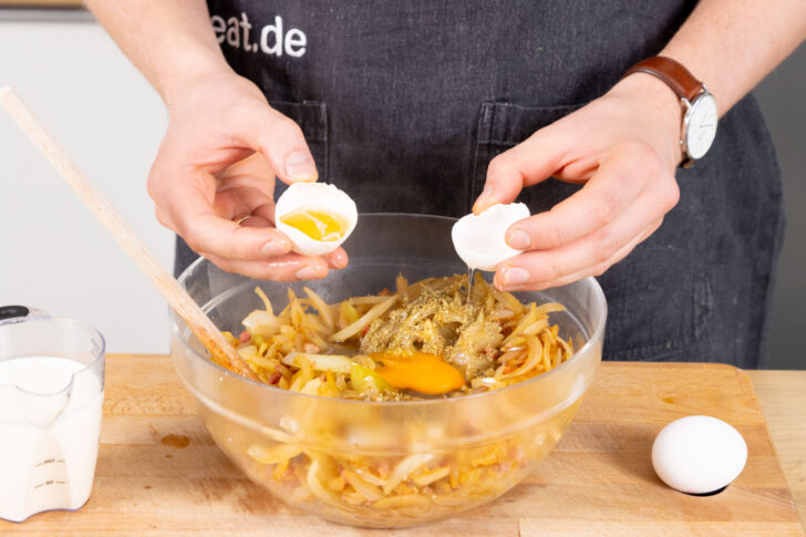 Eier zu den Zwiebeln schlagen.