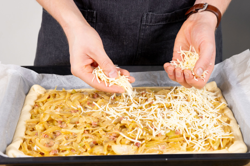 Käse über den Zwielbucken mit Pizzateig geben.