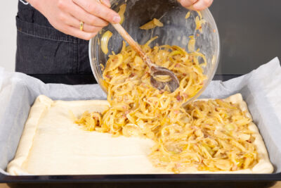Zwiebel-Sahn Gemisch auf dem Teig verteilen.