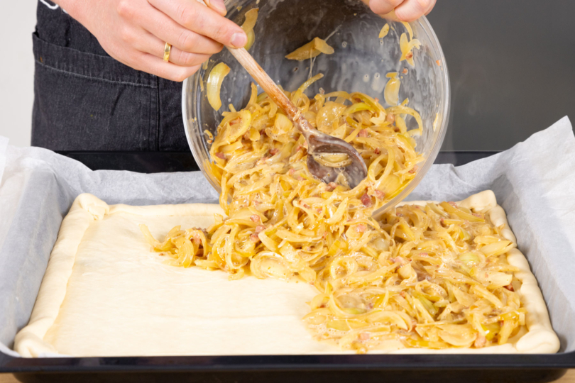 Zwiebel-Sahn Gemisch auf dem Teig verteilen.